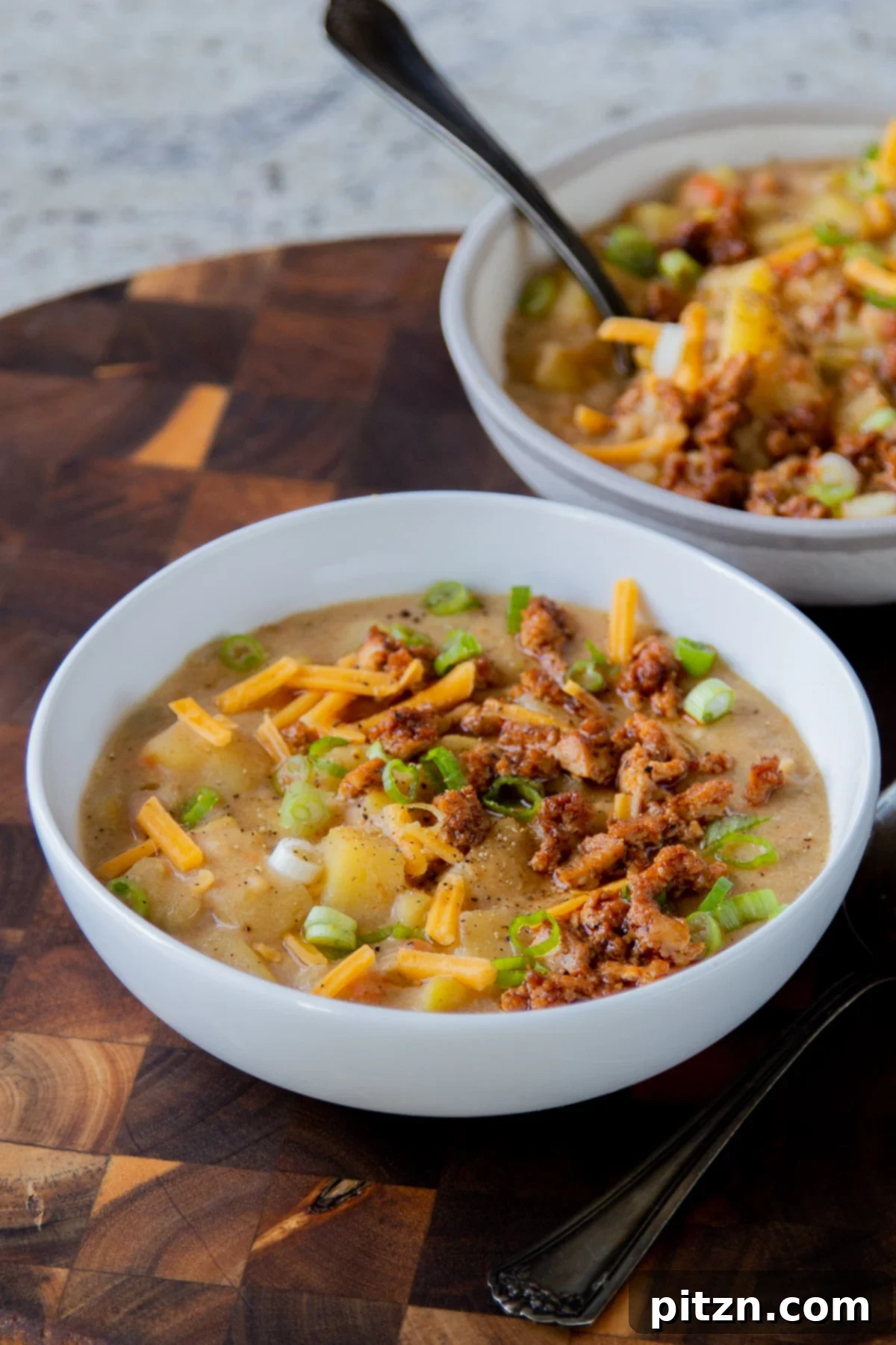 Fireside Smoked Potato Soup 3 Two bowls of richly textured vegan potato soup adorned with a generous sprinkle of smoky crumbled tofu and fresh herbs