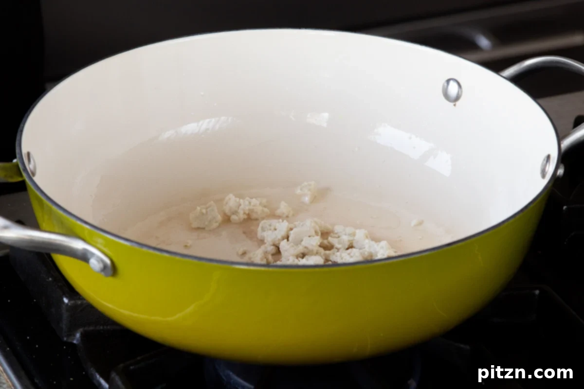 Fireside Smoked Potato Soup 6 Crumbled extra-firm tofu being sautéed in a green non-stick pan, starting to brown on the edges