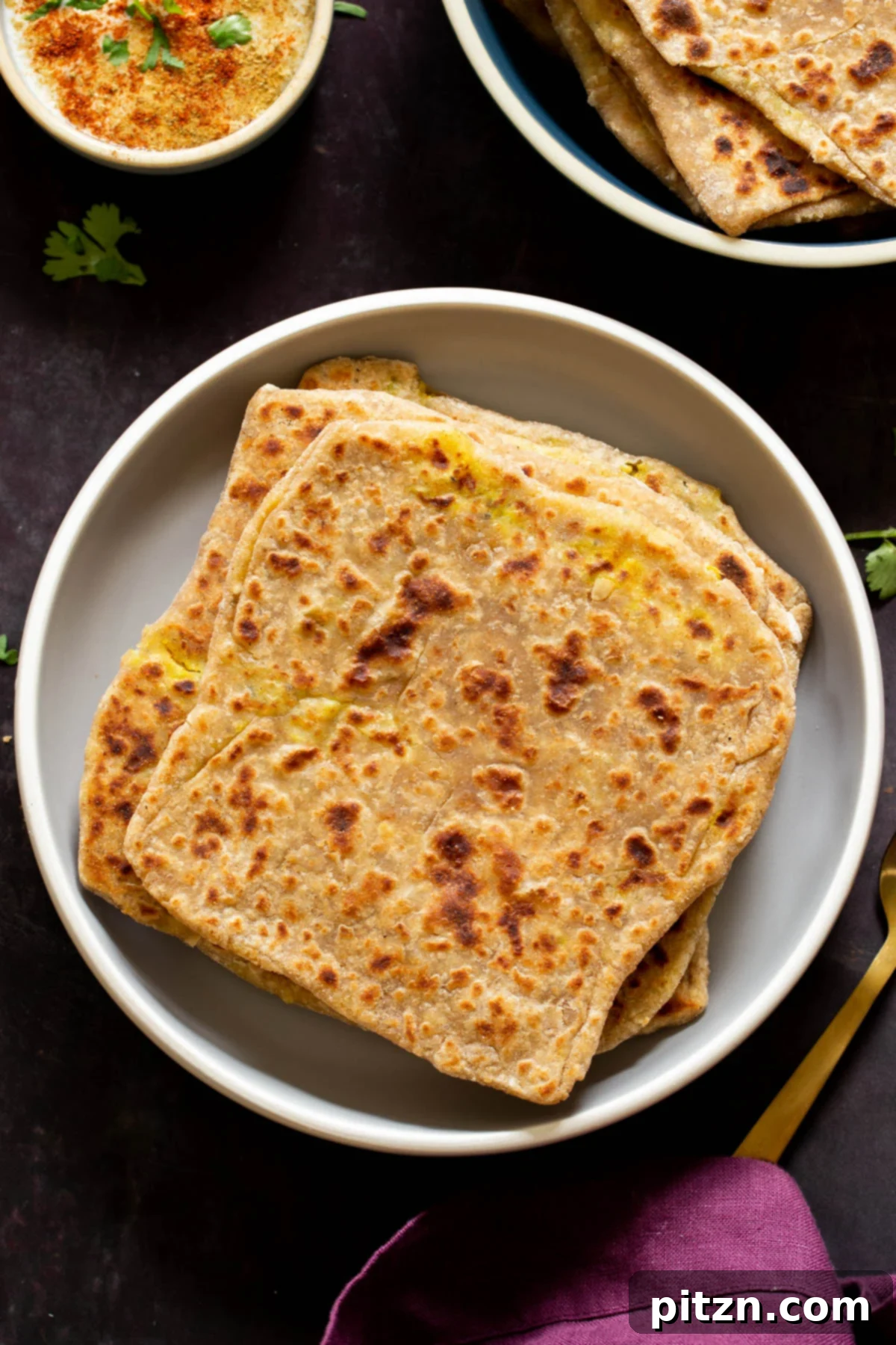 Piled high, golden-brown multigrain aloo parathas on a rustic plate, ready to be enjoyed.