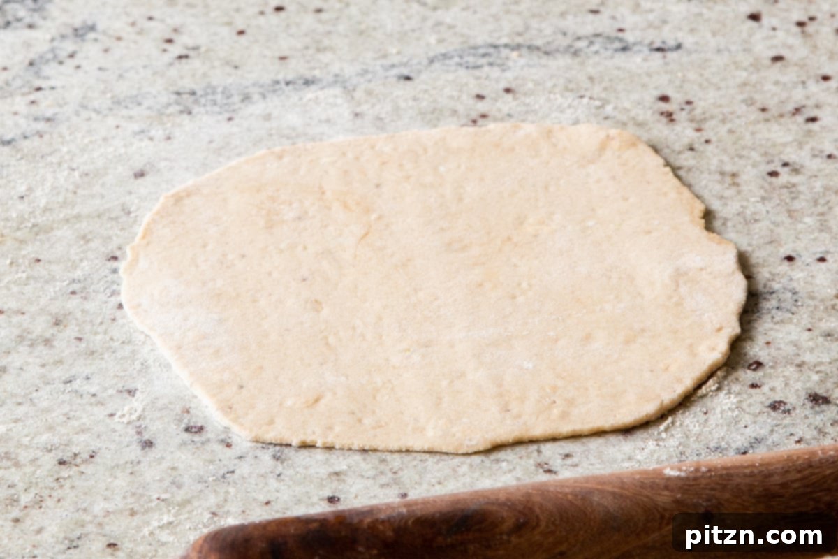 A rolled-out circle of paratha dough on a lightly oiled countertop, showcasing its even thickness and readiness for filling.