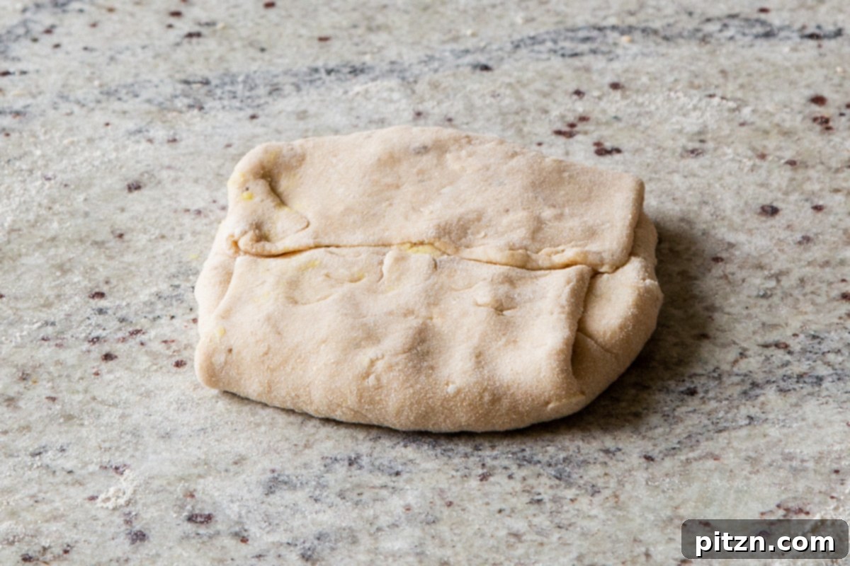 A stuffed aloo paratha after being neatly folded into a square, waiting to be rolled out and cooked.
