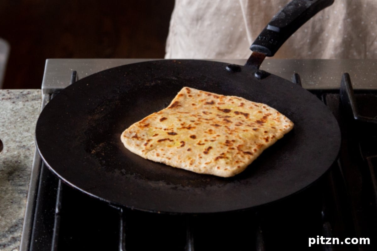 A multigrain aloo paratha beautifully browned on one side, just flipped on the skillet to cook the other side.