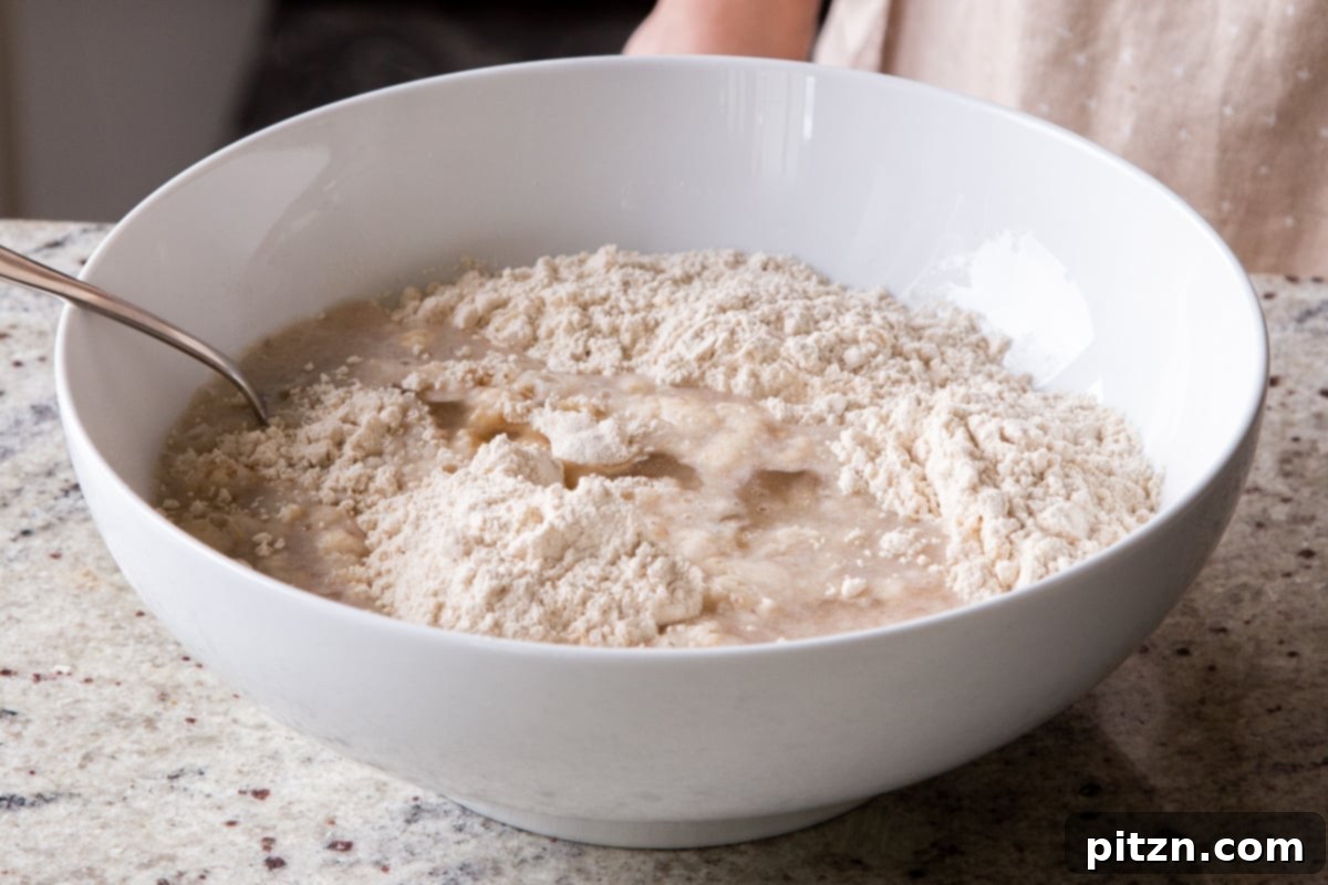 The paratha dough after the initial addition of wet ingredients, showing a coarse, partially mixed texture before thorough kneading.