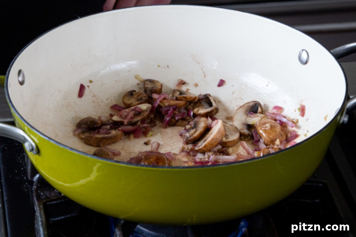 Hearty One-Pot Mushroom Noodle Delight 10 The cooked down mixture of mushrooms, onion, and garlic in the pan, forming a flavorful base.