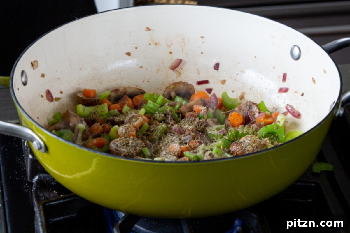 Hearty One-Pot Mushroom Noodle Delight 12 A mix of sauces and spices being added to the sautéed mushrooms, celery, and carrots in the pan.