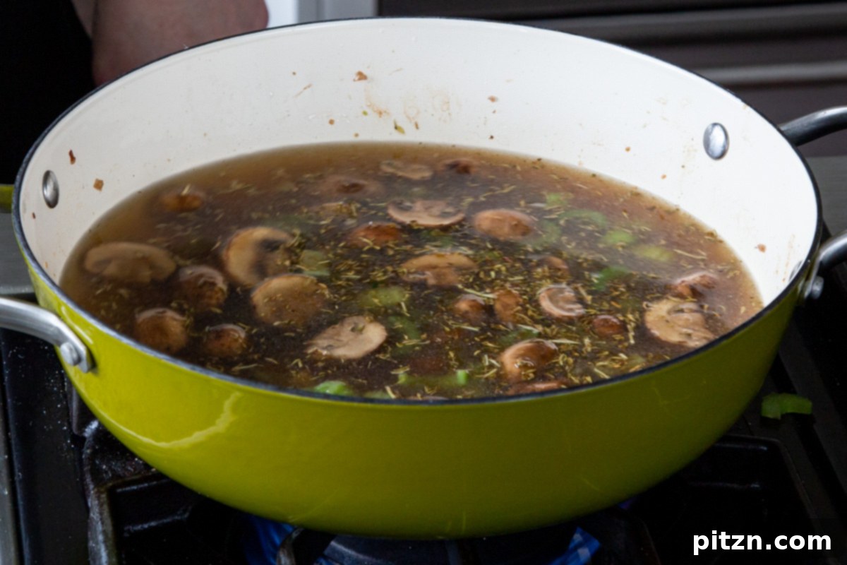 Hearty One-Pot Mushroom Noodle Delight 14 The mushroom mixture in the pan after broth has been added, simmering gently.