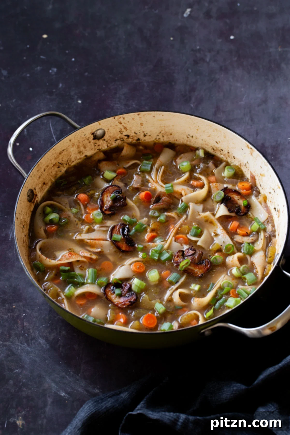 Hearty One-Pot Mushroom Noodle Delight 3 An angled shot of the mushroom noodle soup simmering in a pan, highlighting the vibrant vegetables and noodles.