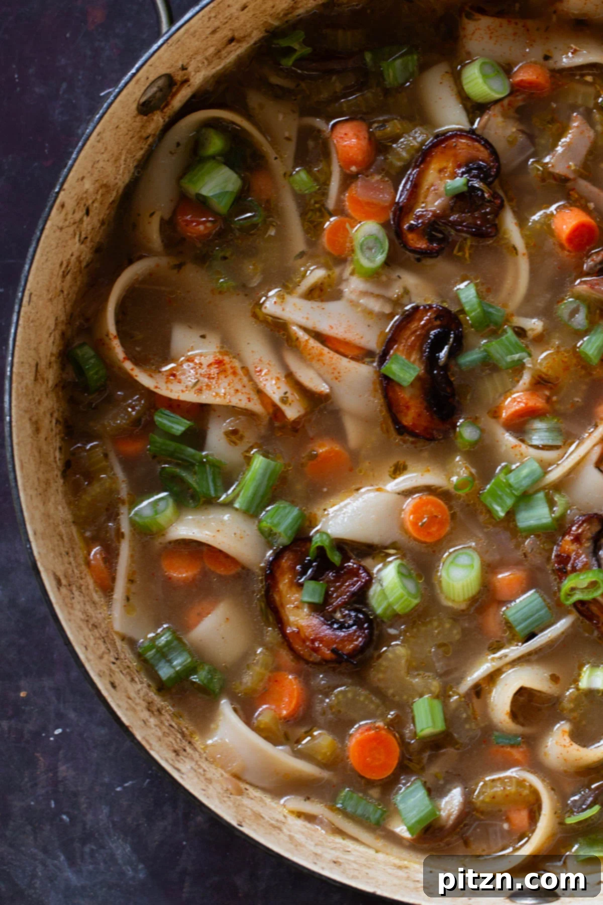 Hearty One-Pot Mushroom Noodle Delight 4 A close-up view of the rich, brothy mushroom noodle soup in the pan, ready to be served.