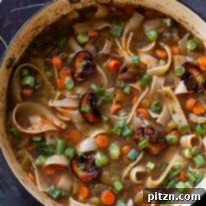 Mushroom noodle soup in a pan, featuring tender noodles and rich broth.