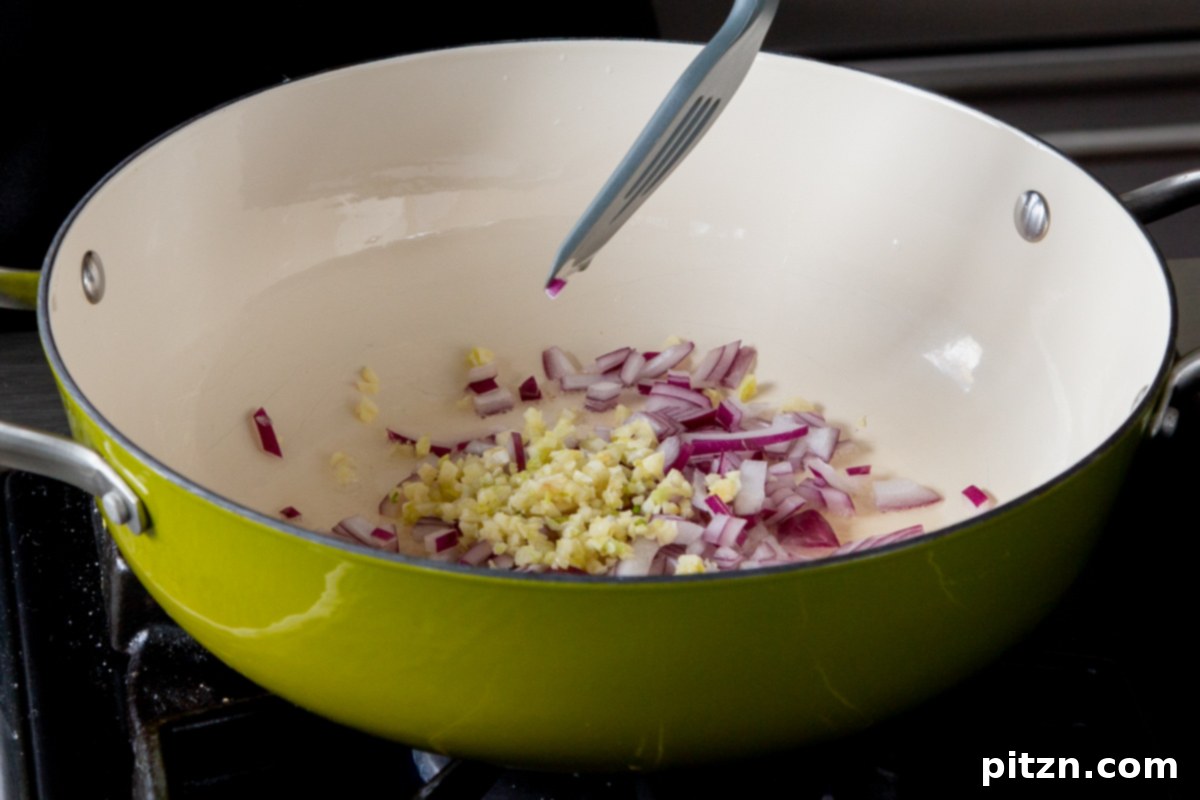 Hearty One-Pot Mushroom Noodle Delight 8 Chopped onion and minced garlic being sautéed in a pan with oil, creating an aromatic base for the soup.