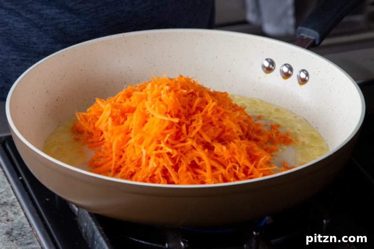 Decadent Carrot Halwa Gateau 10 Adding shredded carrots to the melted vegan butter in the pan, preparing for caramelization.