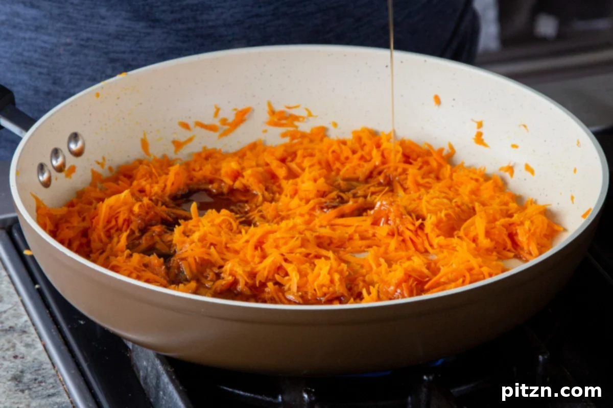 Decadent Carrot Halwa Gateau 11 Pouring maple syrup into the pan with shredded carrots, adding natural sweetness.