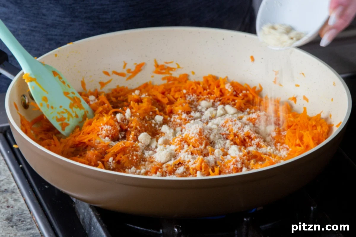 Decadent Carrot Halwa Gateau 12 Adding almond flour to the shredded carrot mixture in the pan, contributing to texture and flavor.