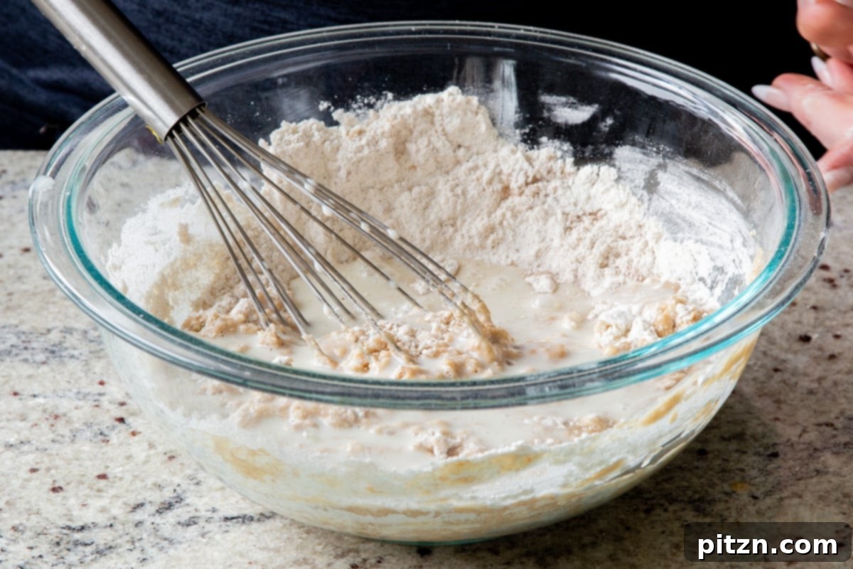 Decadent Carrot Halwa Gateau 20 Mixing half of the dry ingredients into the wet ingredients, a crucial step for cake batter.