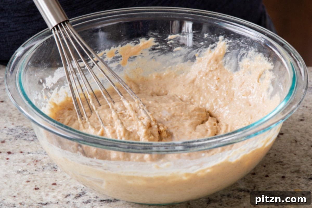 Decadent Carrot Halwa Gateau 21 Mixing the remaining dry ingredients into the wet mixture until a smooth cake batter is formed.