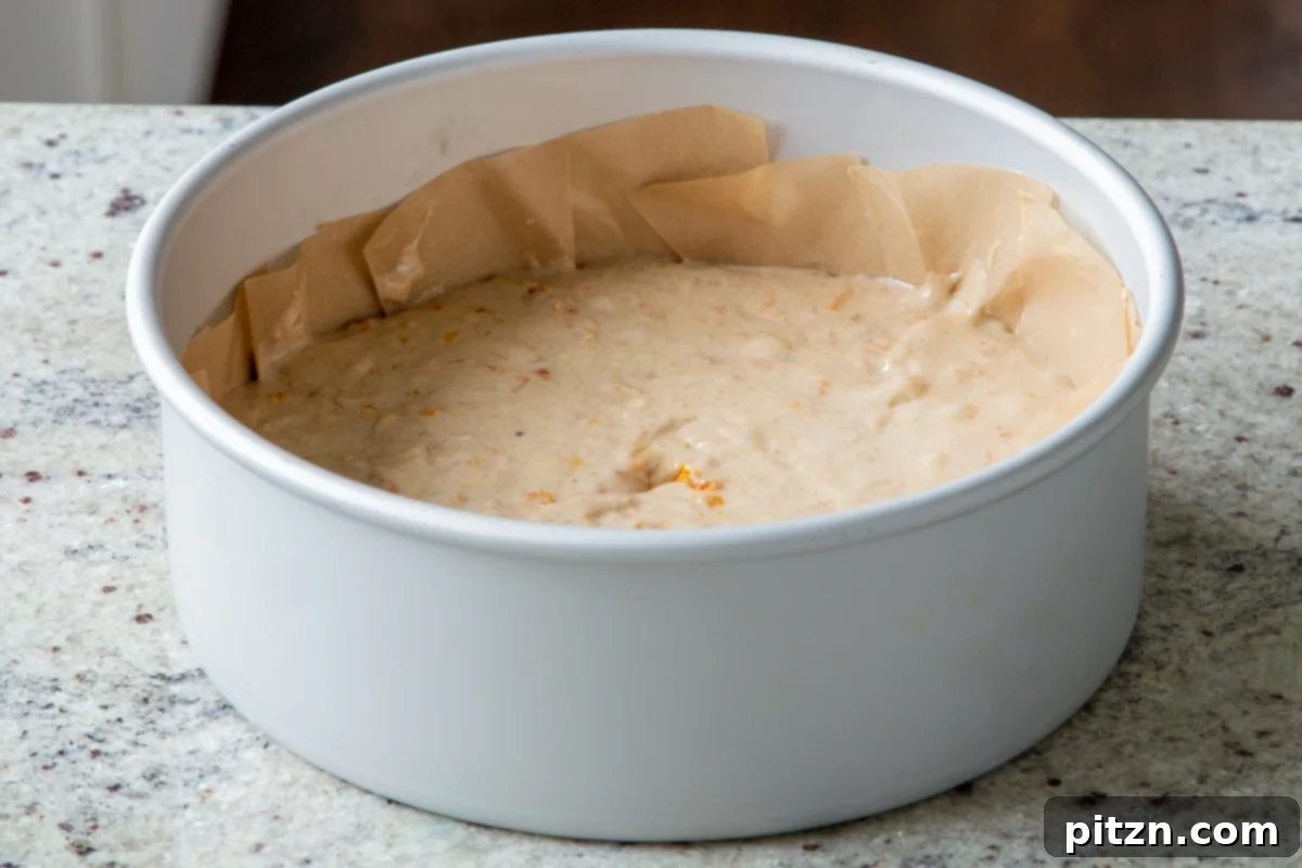 Decadent Carrot Halwa Gateau 25 Cake batter poured into a parchment-lined metal cake pan, ready for the next step.