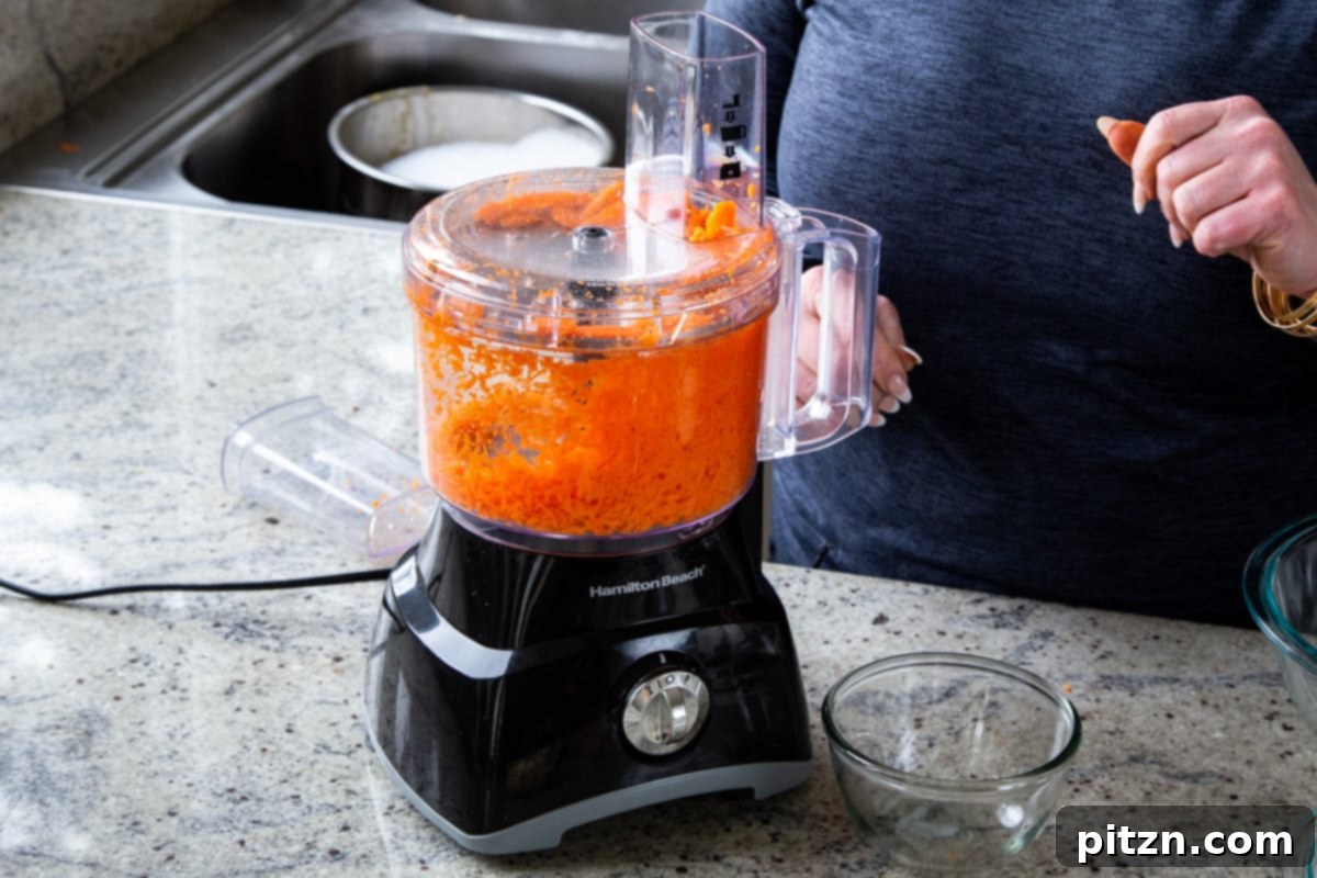 Decadent Carrot Halwa Gateau 8 Finely shredded carrots in a food processor, highlighting the preparation process for the halwa topping.