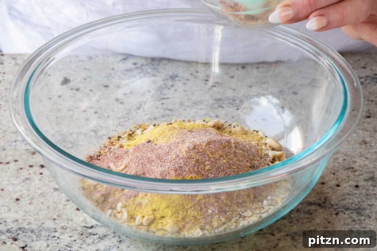 Doritos Nacho Crunch Bars 9 Adding mixed spices to the bowl of oats, nuts, and almond flour