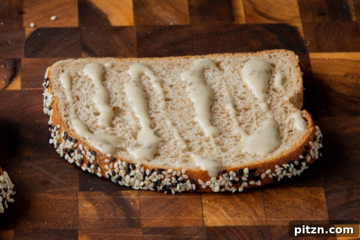 Plant-Based Deli Club 13 A slice of golden-brown toasted bread with a creamy layer of vegan mayonnaise, ready for sandwich fillings.