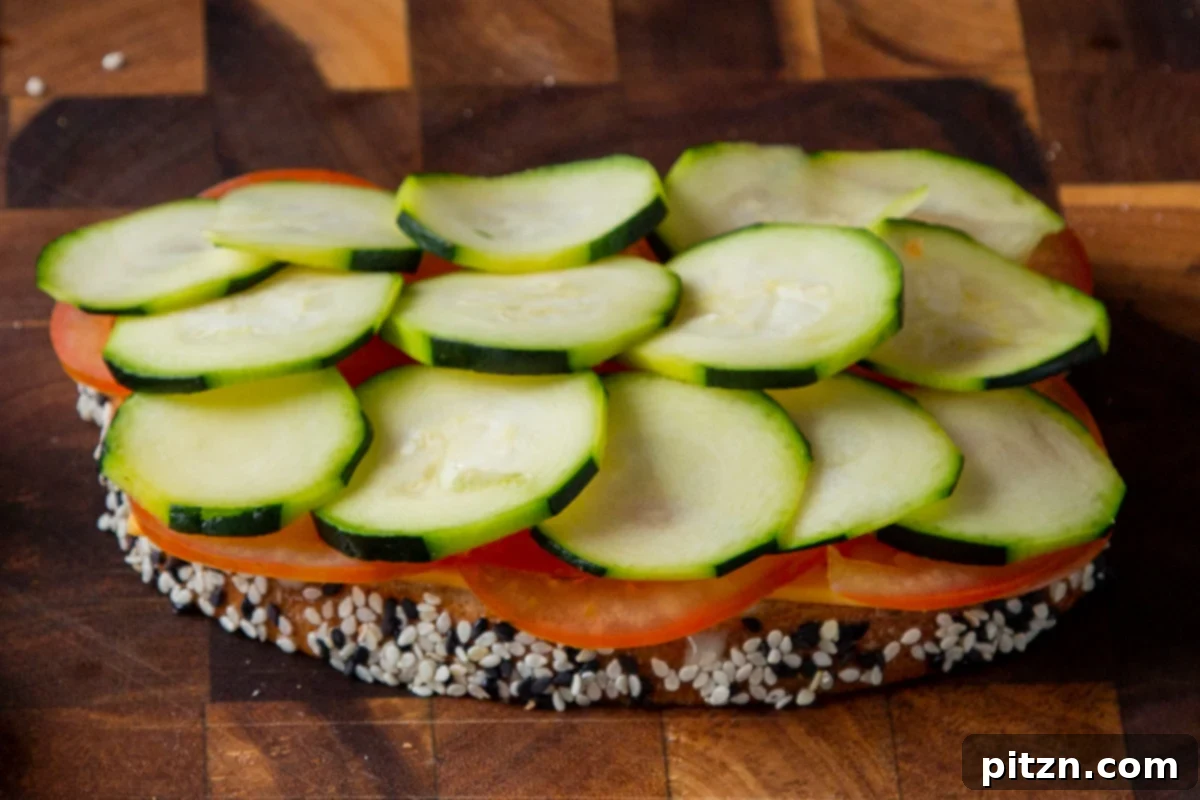 Plant-Based Deli Club 14 Freshly sliced tomatoes and crisp cucumber arranged neatly on a slice of bread with vegan mayo, forming the first layer of the sandwich.