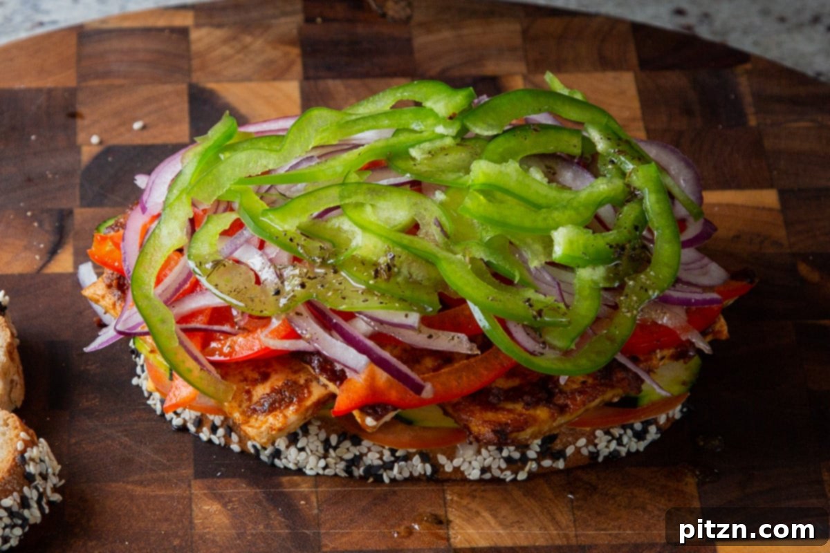Plant-Based Deli Club 17 Crisp green bell pepper slices being added to the top of the sandwich layers, completing the fresh vegetable assembly.