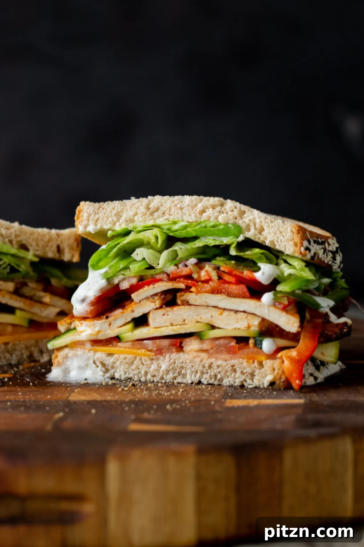 Plant-Based Deli Club 4 A beautifully layered vegan club sandwich, sliced in half to showcase the vibrant fresh fillings and homemade tofu deli meat.