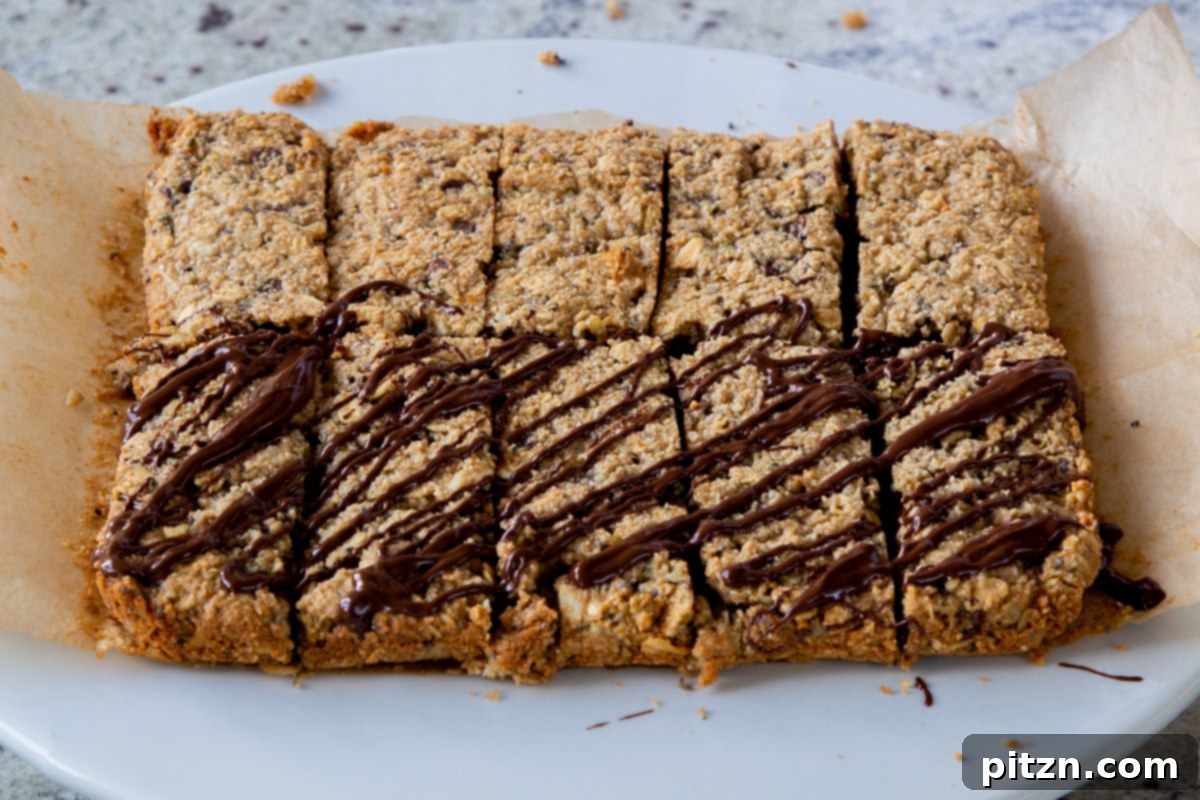 Perfectly Crisp Granola Bars 18 baked granola bars, after slicing, being drizzled with melted chocolate