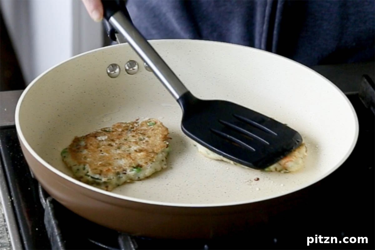 Golden brown Rava Idli pancakes perfectly cooked in a pan, showcasing their fluffy texture and savory appeal, ready to be served.