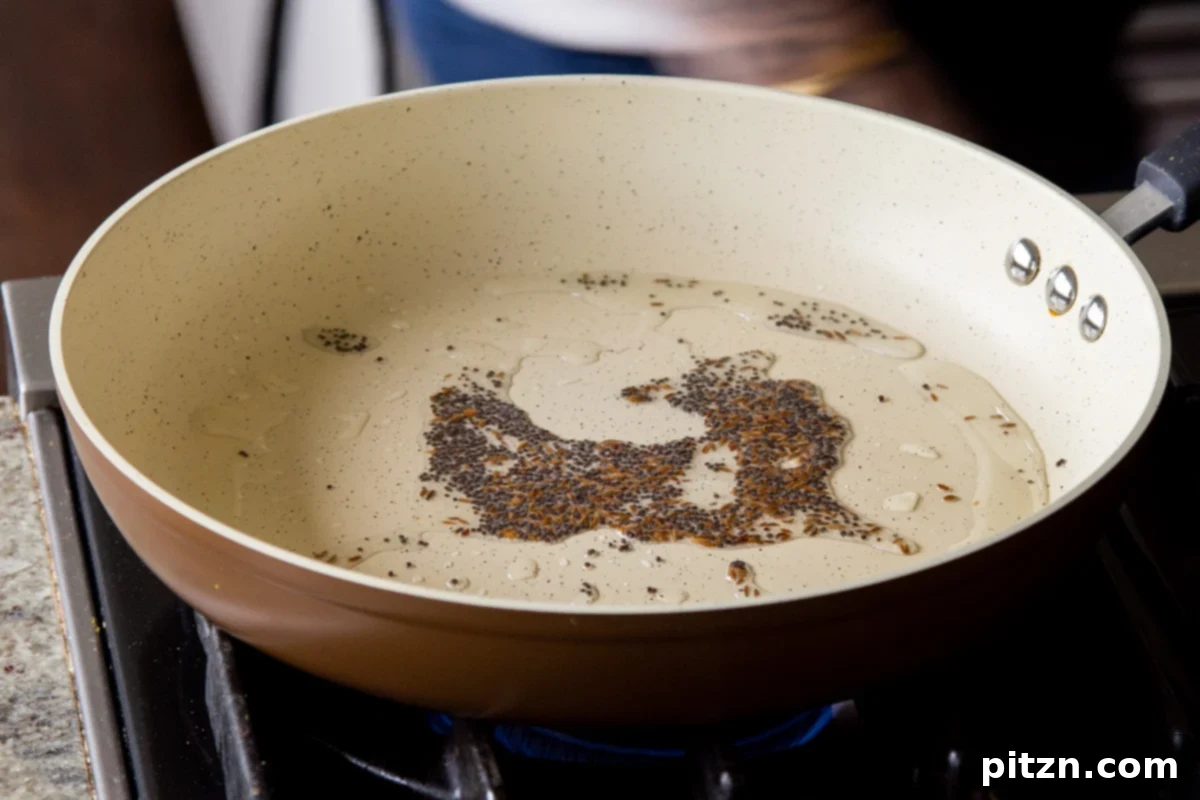 Toasted mustard and cumin seeds in a pan, lightly browned and fragrant, after tempering, forming the flavorful base for Rava Idli Waffles.