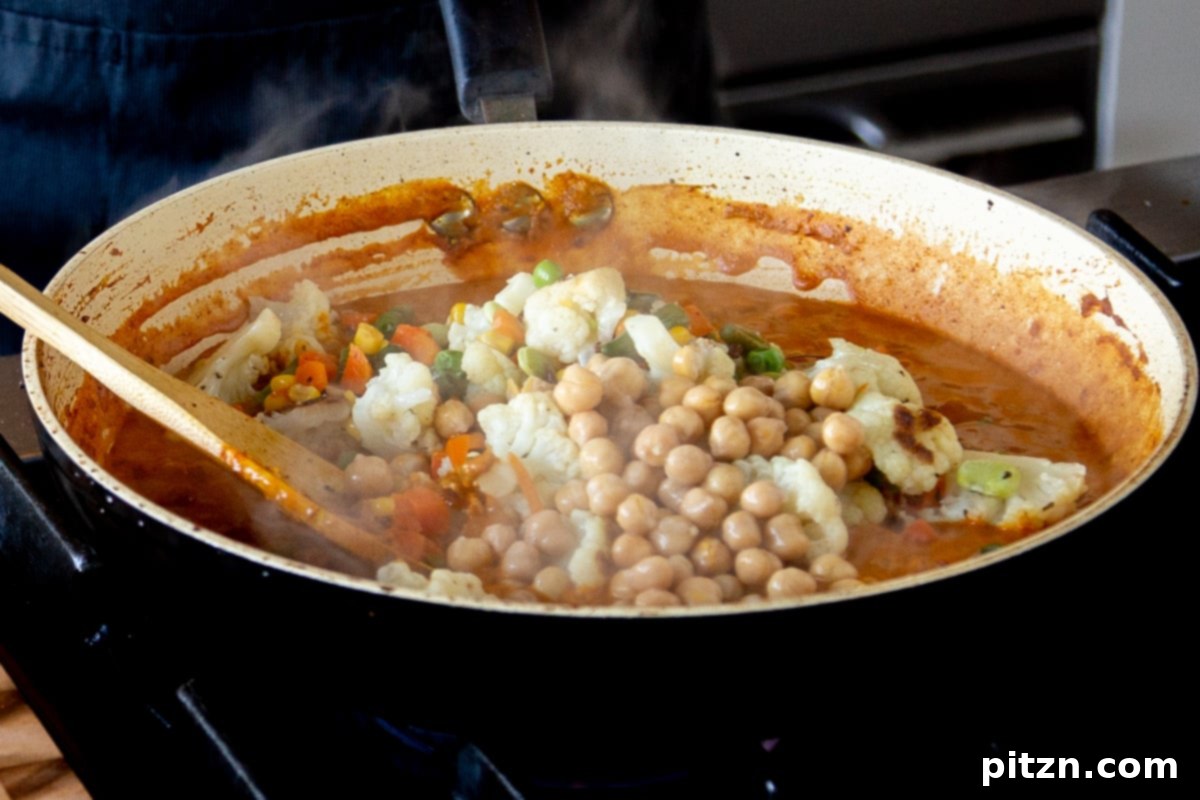 North Indian Restaurant Bhuna: A Vegetarian Curry Classic 14 adding cooked vegetables and chickpeas to the bhuna masala sauce in the pan