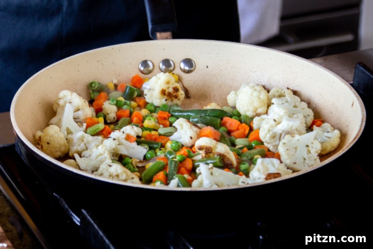 North Indian Restaurant Bhuna: A Vegetarian Curry Classic 8 adding the rest of the mixed vegetables to the cauliflower in the pan
