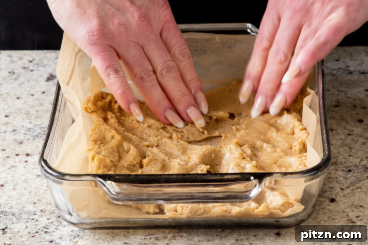 pressing the dough into the lined baking pan