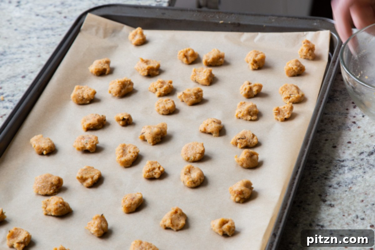 The unbaked almond flour croutons, neatly arranged and spaced on a baking sheet lined with parchment paper, awaiting their transformation in the oven.