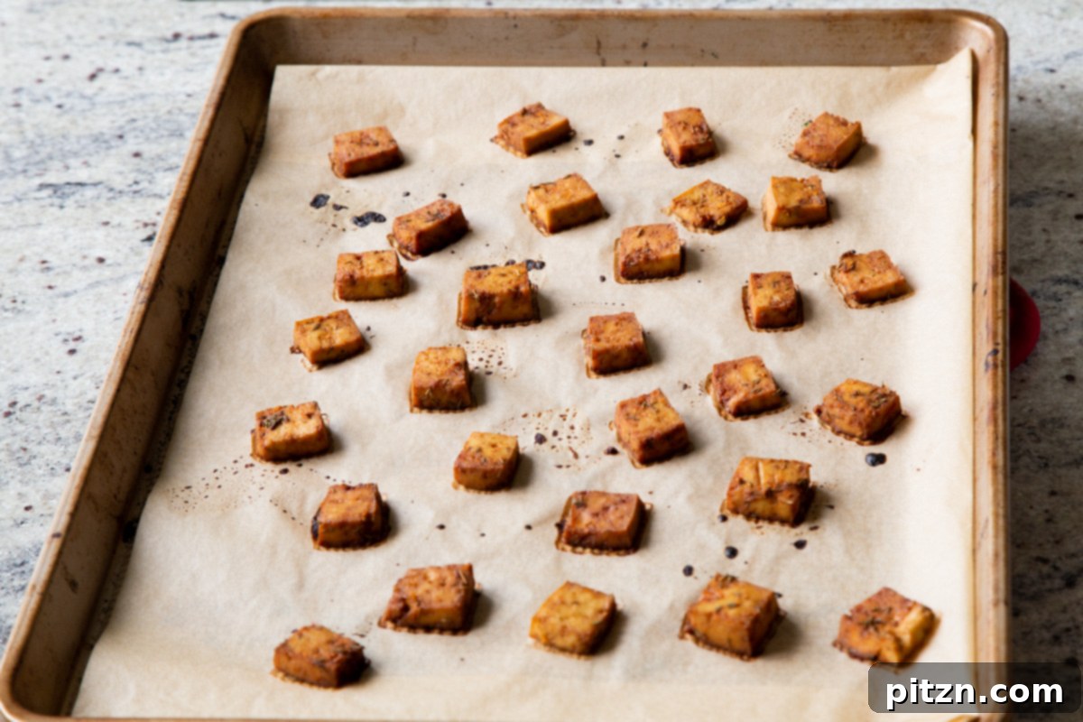 Perfectly baked smoky tofu pieces, golden and slightly crisped, resting on a baking sheet after being removed from the oven.