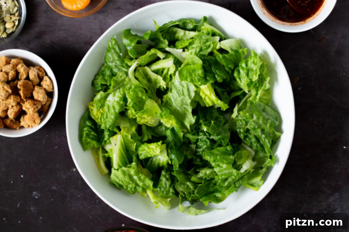 Fresh, vibrant lettuce forming the base of the salad in a serving bowl, ready for the addition of other colorful ingredients.