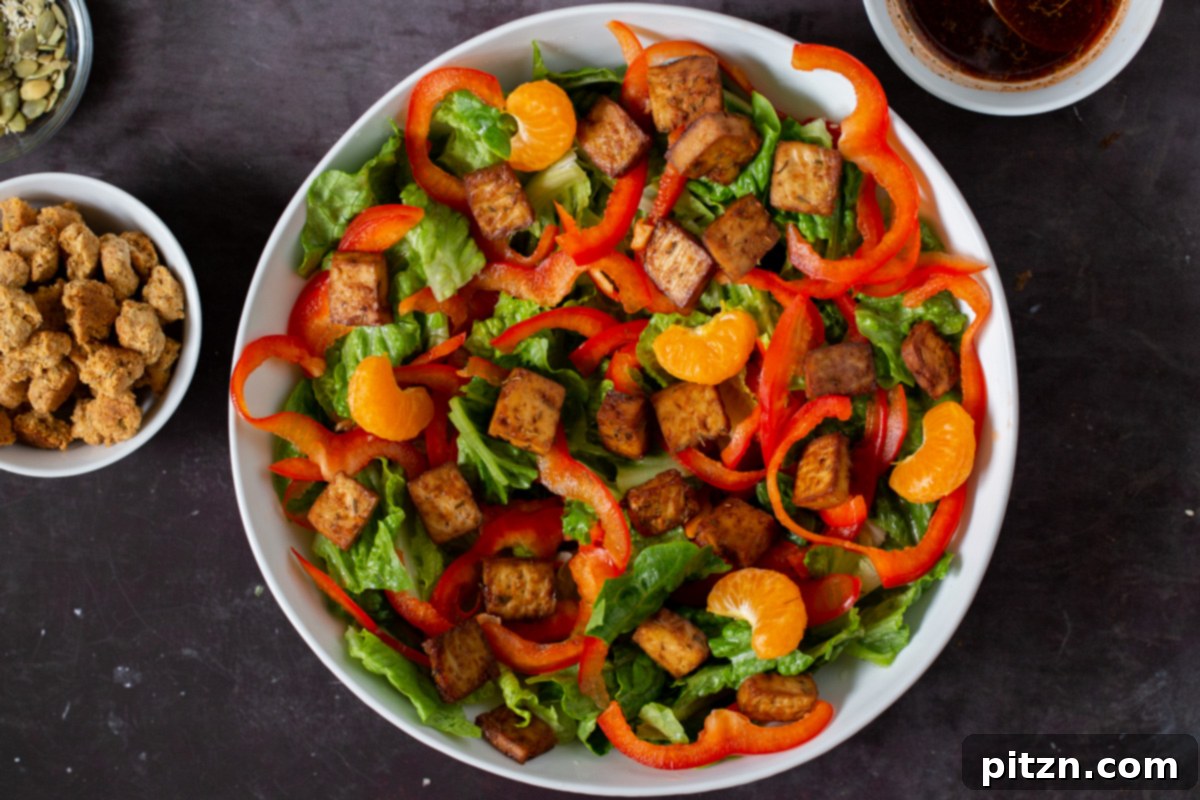 Fresh orange segments being artfully placed into the salad bowl, adding a sweet, tangy, and refreshing burst of flavor.