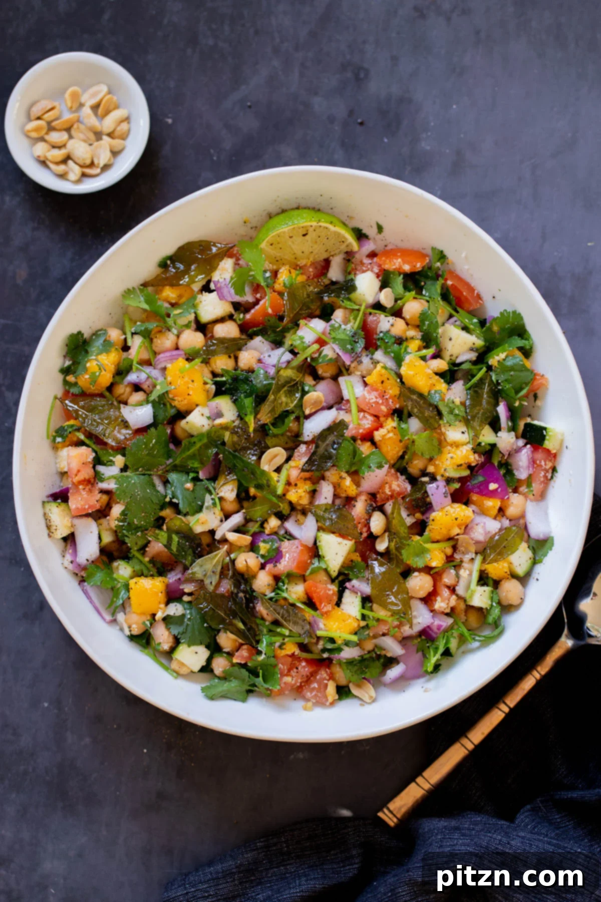 Fragrant Curry Leaf Mango Chickpea Zucchini Koshimbir 2 A vibrant zucchini koshimbir salad served in a elegant bowl, garnished with a fresh lime wedge and cilantro, ready to be enjoyed.