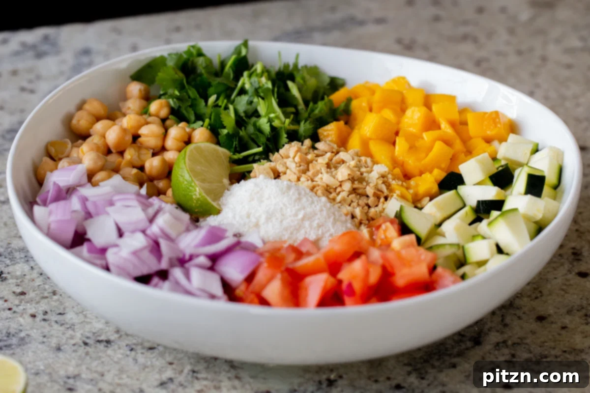 Fragrant Curry Leaf Mango Chickpea Zucchini Koshimbir 14 A large bowl filled with all the Koshimbir salad ingredients, including zucchini, mango, chickpeas, and seasonings, thoroughly mixed before the tempering is added.