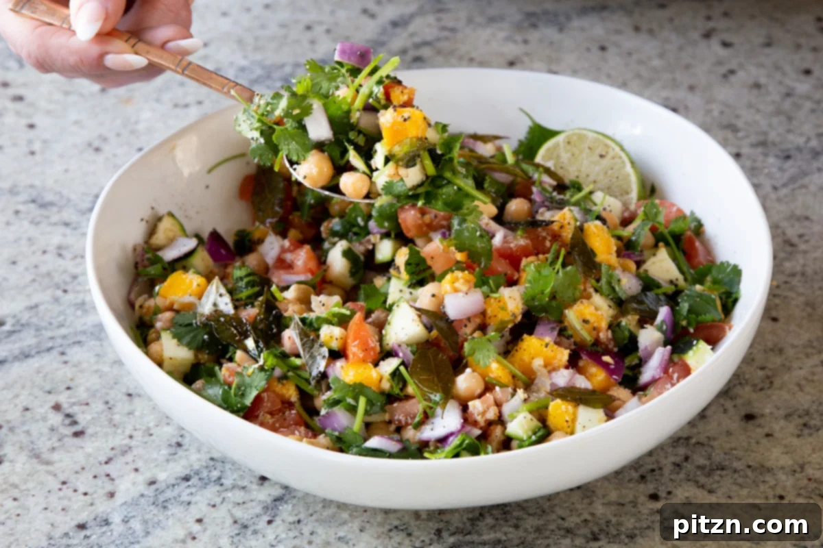 Fragrant Curry Leaf Mango Chickpea Zucchini Koshimbir 17 A serving spoon lifting a spoonful of the colorful and textured Koshimbir salad from the bowl, ready to be enjoyed.