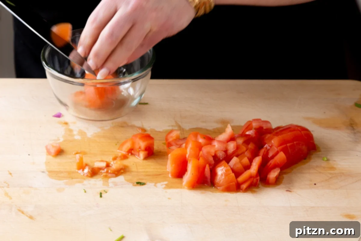 Fragrant Curry Leaf Mango Chickpea Zucchini Koshimbir 7 A close-up of hands expertly chopping ripe tomatoes on a cutting board, preparing them for the vibrant Koshimbir salad.