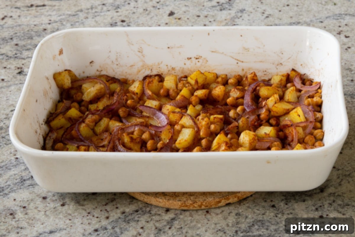 Smoky Chickpea Potato Salad 10 Roasted chickpeas, onions, and potatoes in a baking dish after 15 minutes in the oven, showing early caramelization.