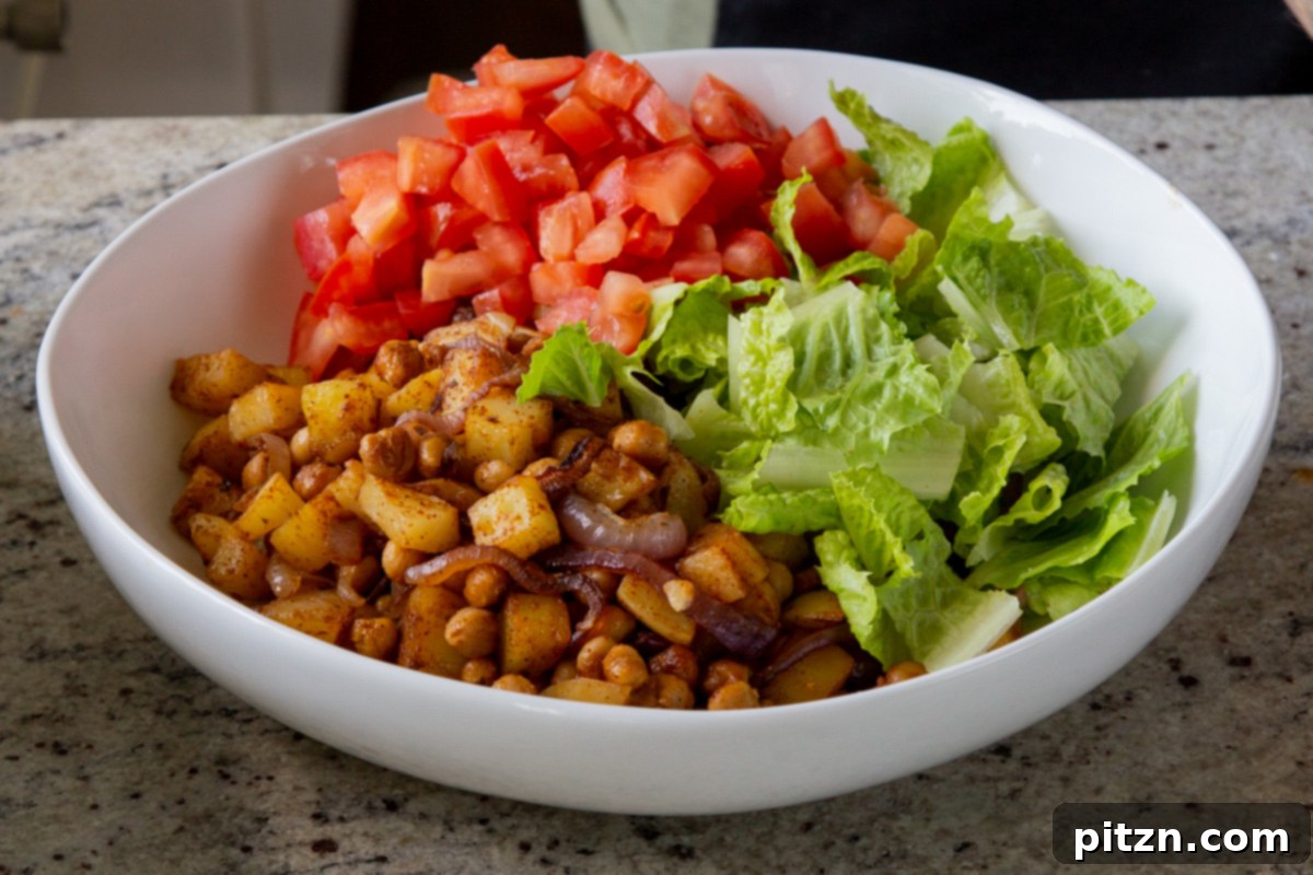 Smoky Chickpea Potato Salad 15 Diced fresh tomatoes being added to the salad bowl, bringing color and juiciness to the mixture.