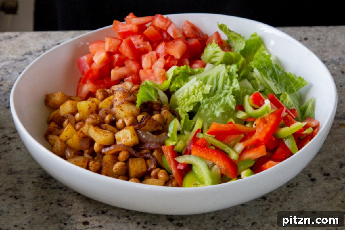 Smoky Chickpea Potato Salad 16 Brightly chopped bell peppers being added to the large salad bowl, enhancing the salad's freshness and visual appeal.