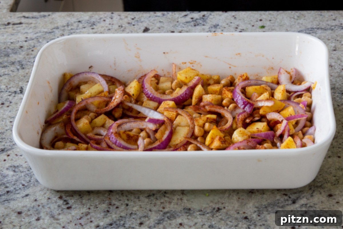 Smoky Chickpea Potato Salad 9 Chickpeas, onions, and potatoes in a baking dish, now thoroughly tossed and coated with BBQ seasoning, ready for the oven.
