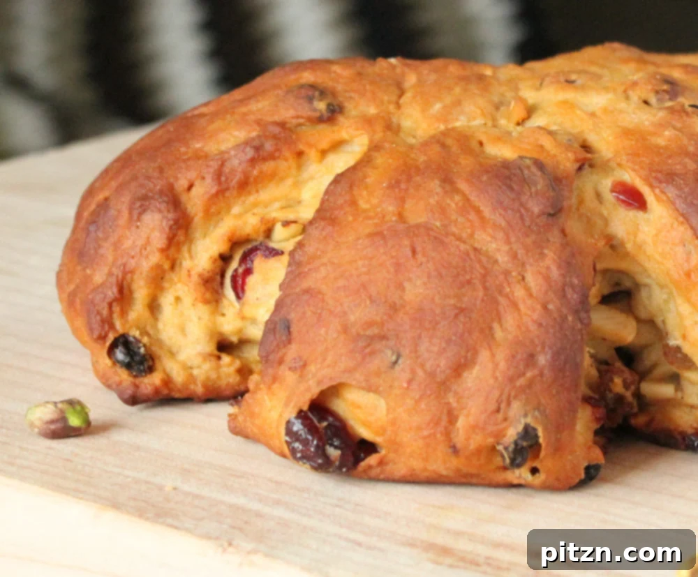 A close-up of a festive Vegan Stollen Wreath, showcasing its golden crust and the inviting texture of the dough embedded with fruits and nuts.