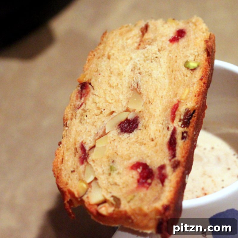 A perfectly baked slice of Vegan Christmas Stollen Wreath, showcasing the vibrant and well-distributed cranberries, pistachios, and candied orange within the soft, spiced bread.