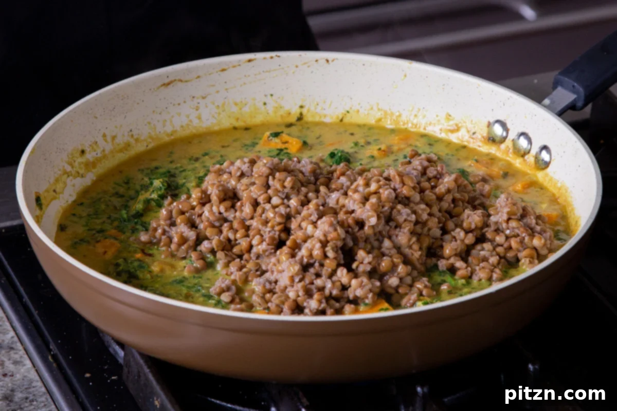 Adding pre-cooked lentils to the pan with the simmering sweet potato coconut curry.