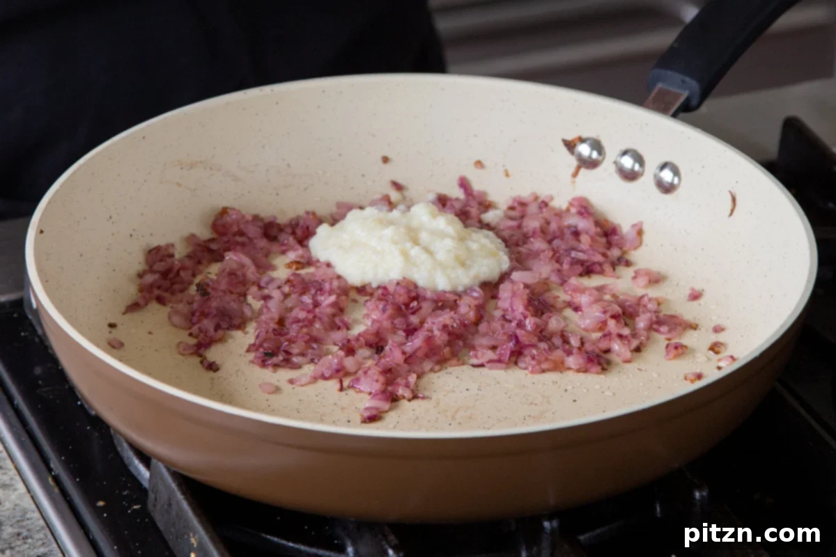 Incorporating ginger-garlic paste into the cooked onions, enhancing the aromatic foundation of the curry.