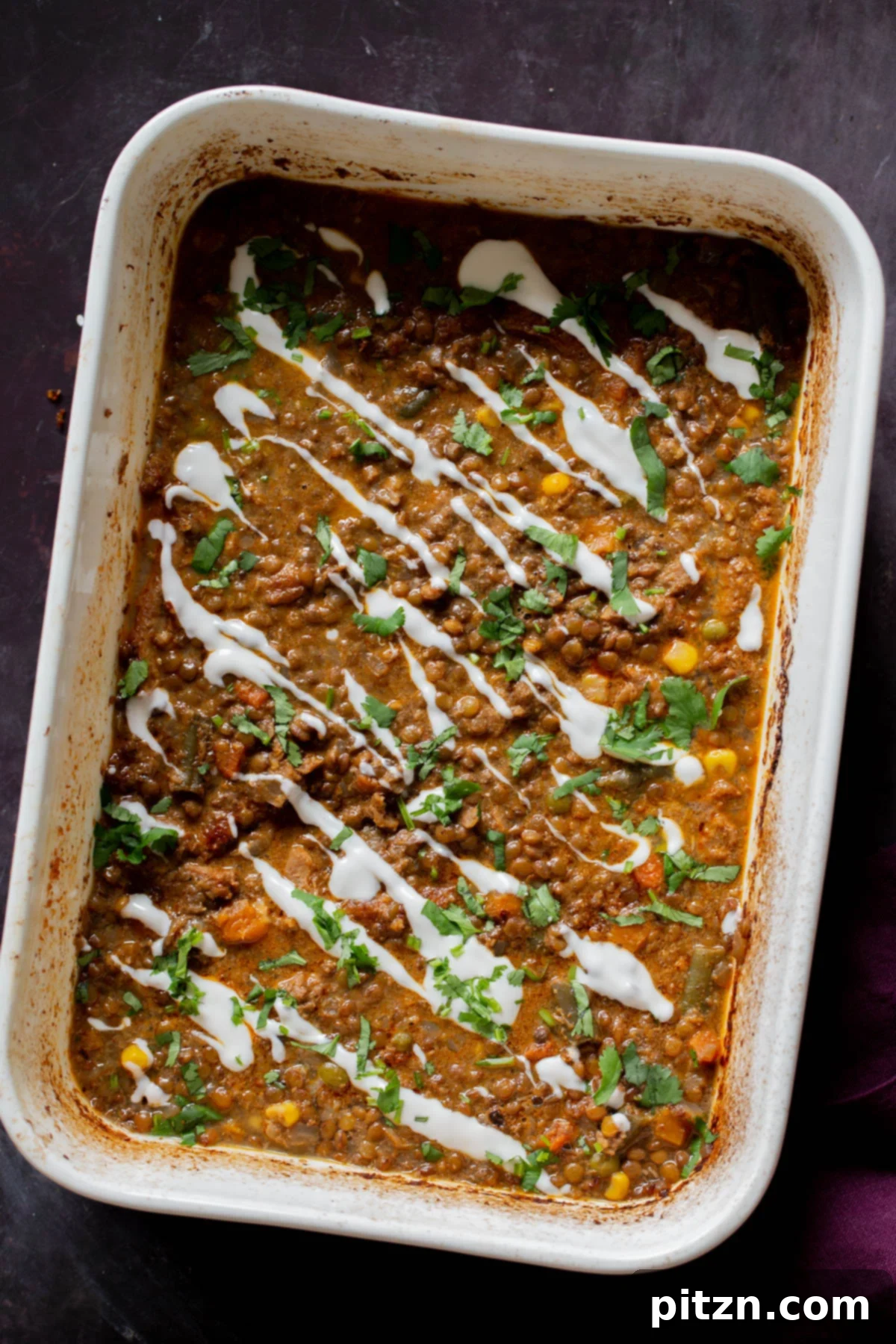Sheet Pan Konkani Lentil Curry 2 Konkani curry dal casserole topped with coconut cream, cilantro, and pepper flakes in the baking pan