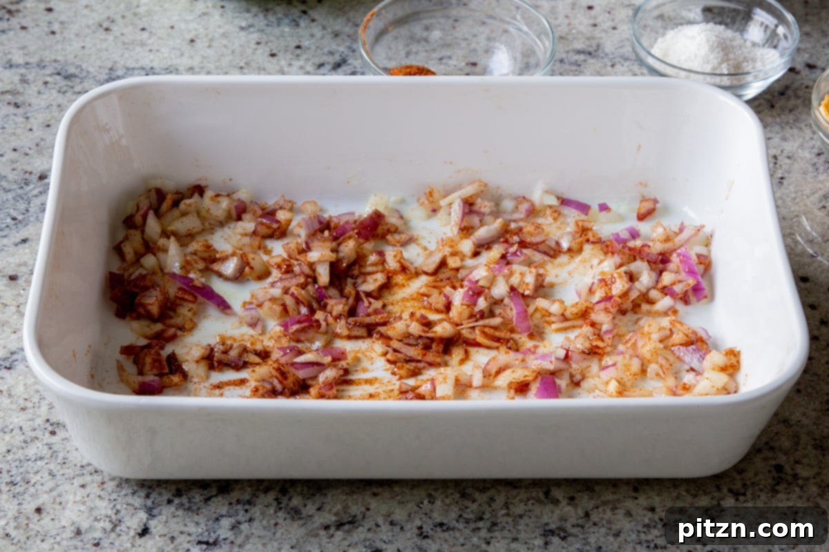 Sheet Pan Konkani Lentil Curry 9 adding onion, ginger, and garlic mixed with the spices in the baking pan, before baking